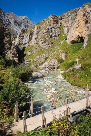 Photo for Mountain river and wood bridge in Vanoise national Park alpine valley, Savoie, French alps - Royalty Free Image