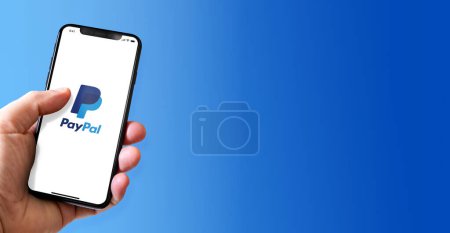 Photo for Paris - France - March 15, 2022 : Hand holding iphone smartphone with Paypal logo. Horizontal banner - Royalty Free Image
