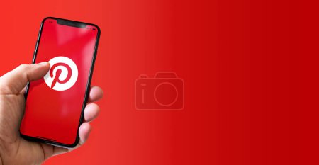 Photo for Paris - France - March 15, 2022 : Hand holding iphone smartphone with Pinterest logo. Horizontal banner - Royalty Free Image