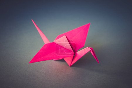 Foto de Origami de grúa de papel rosa aislado sobre un fondo gris en blanco. - Imagen libre de derechos