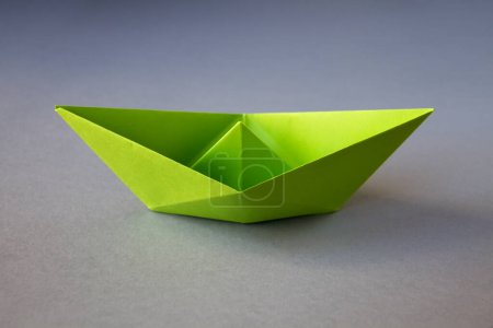 Photo for Green paper boat origami isolated on a blank grey background. - Royalty Free Image