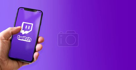 Photo for Paris - France - March 15, 2022 : Hand holding iphone smartphone with Twitch logo. Horizontal banner - Royalty Free Image