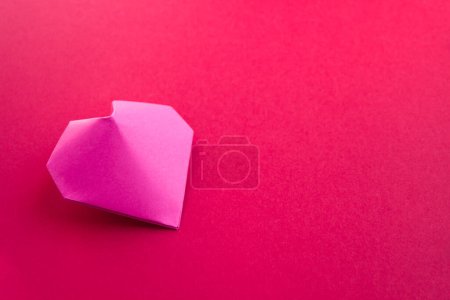 Foto de Origami de corazón de papel rosa aislado sobre un fondo rojo en blanco. Tarjeta de San Valentín - Imagen libre de derechos
