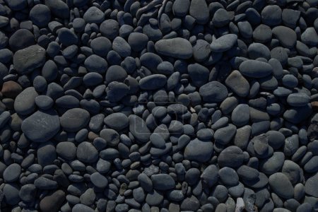 Téléchargez les photos : Des cailloux noirs sur une plage. texture de fond. Papier peint horizontal - en image libre de droit