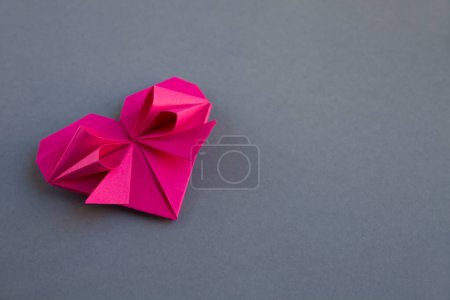 Foto de Origami corazón de papel rosa aislado sobre un fondo gris en blanco. Tarjeta de San Valentín - Imagen libre de derechos