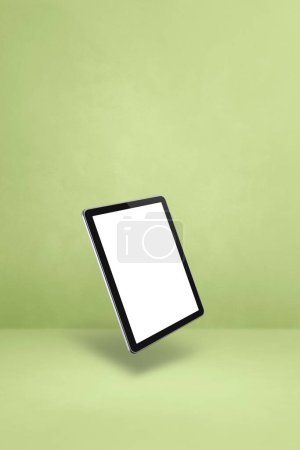 Téléchargez les photos : Tablette vierge pc ordinateur flottant sur un fond vert. Illustration 3D isolée. Modèle vertical - en image libre de droit