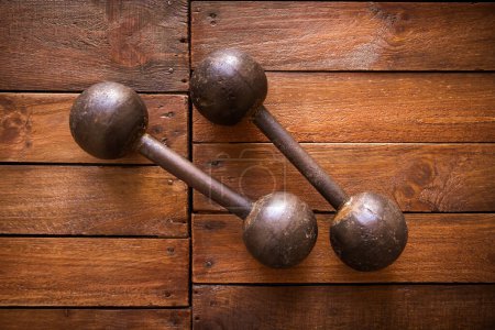 Photo for Old rusty dumbbells on rustic wood board background texture - Royalty Free Image