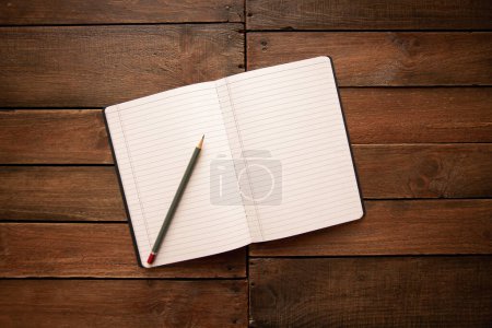 Photo for Open notebook and pencil on a rustic vintage wooden board - Royalty Free Image