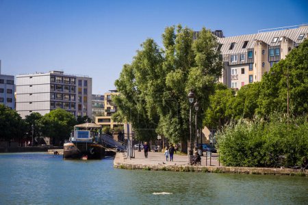 Téléchargez les photos : Paris - France - 05 juin 2023 : Vue sur le canal d'Ourcq et la péniche depuis les berges en été - en image libre de droit