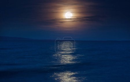 Full moon rising above lake