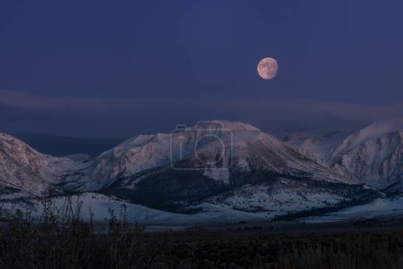Foto de Luna llena elevándose sobre montañas nevadas - Imagen libre de derechos