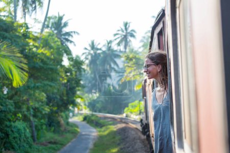 Mujer Yong disfrutando del viaje en tren de Ella a Kandy entre plantaciones de té en las tierras altas de Sri Lanka