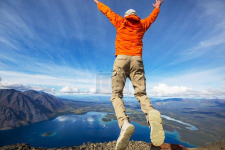 Foto de Saltando hombre por encima de las montañas lago - Imagen libre de derechos