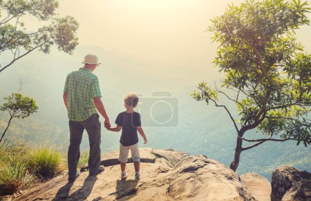 Foto de Father and son  on the cliff in Sri Lanka mountains. Happy vacation scene - Imagen libre de derechos