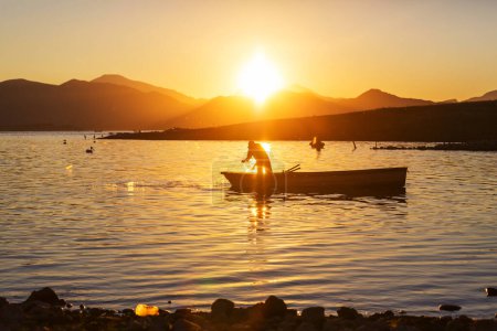 Téléchargez les photos : Pêcheurs en bateaux sur le lac au lever du soleil - en image libre de droit