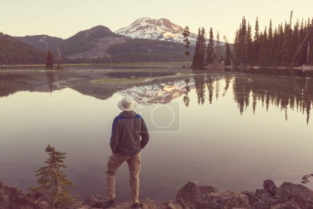 A man is resting at ease by the calm lake. Relaxation vacation