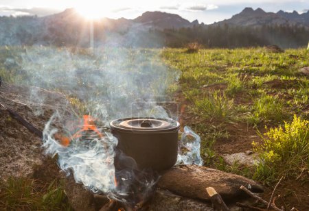 Foto de Hervidor turístico en llamas de fogata en camping en la caminata. Cocinar comida en el bosque con leña de madera. - Imagen libre de derechos