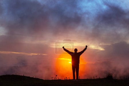 Téléchargez les photos : Homme heureux debout sur une falaise au coucher du soleil
. - en image libre de droit