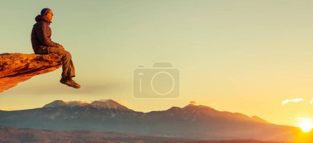 Téléchargez les photos : Homme sur la falaise des montagnes au lever du soleil. Scène de randonnée. - en image libre de droit
