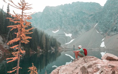 Foto de Un hombre descansa a gusto junto al lago tranquilo. Vacaciones de relajación - Imagen libre de derechos