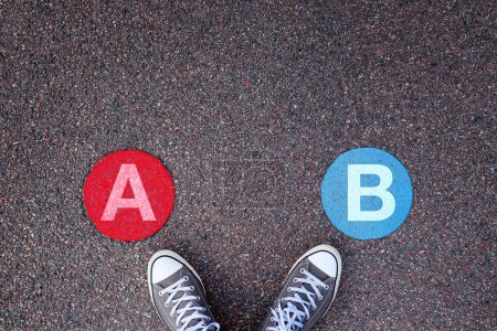 Téléchargez les photos : A ou B, concept à deux options avec baskets sur chaussée asphaltée, vue de dessus - en image libre de droit