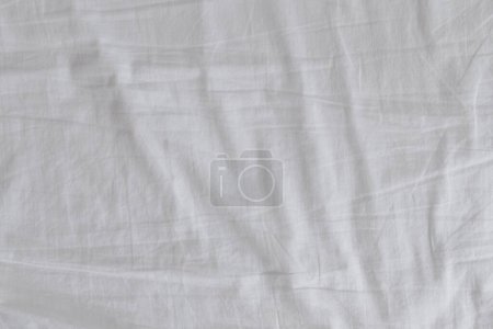 Téléchargez les photos : Draps froissés de lit blanc dans la chambre à coucher comme fond, vue de dessus - en image libre de droit