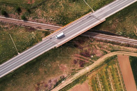Photo for White van crossing the railroad overpass on empty highway, aerial view top down from drone pov image for transportation and delivery business concept - Royalty Free Image