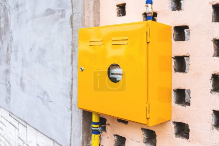 Foto de Medidor de gas en caja metálica amarilla unido a una pared de la casa, enfoque selectivo - Imagen libre de derechos