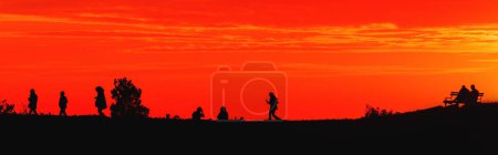 Foto de Silueta de jóvenes al atardecer con hermoso cielo naranja en el fondo, estilo de vida juvenil y concepto divertido - Imagen libre de derechos