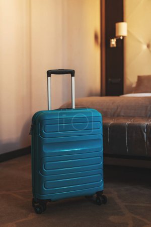 Photo for Blue travel suitcase in hotel apartment bedroom, selective focus - Royalty Free Image