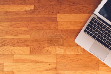 Foto de Laptop on hardwood parquet flooring as copy space, top view - Imagen libre de derechos