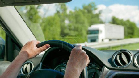Téléchargez les photos : Female hands holding firmly car steering wheel while driving along the freeway, selective focus - en image libre de droit