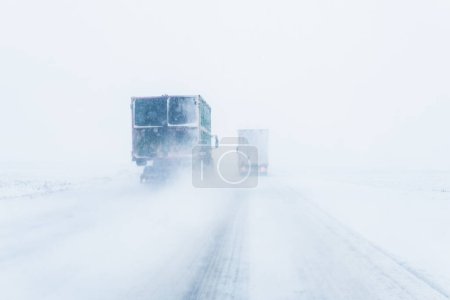 Photo for Freight transportation truck on the road in snow storm blizzard, bad weather conditions for transportation event, selective focus - Royalty Free Image