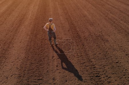 Téléchargez les photos : Rear view aerial of female farmer agronomist standing and looking over ploughed field, drone photography - en image libre de droit