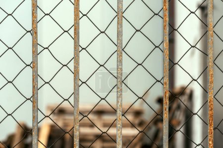 Photo for Chain link diamond pattern wire fence and worn metallic bars as background - Royalty Free Image