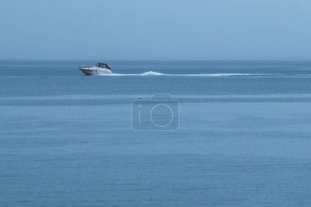 Téléchargez les photos : Small white yacht speeding away across the Kvarner gulf during the autumn rainstorm - en image libre de droit