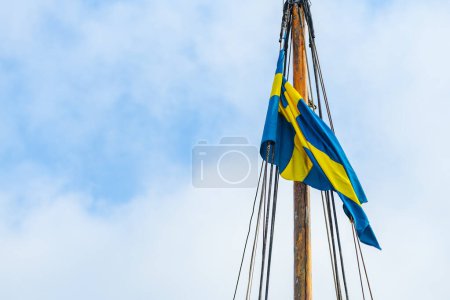 Téléchargez les photos : Drapeau suédois sur un mât de voilier lors d'une journée d'été venteuse à Halmstad, Suède - en image libre de droit