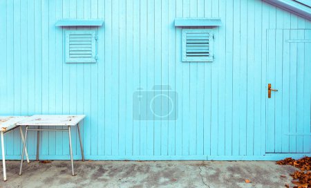 Photo for Blue wooden shed with small windows and two tables in front as background - Royalty Free Image