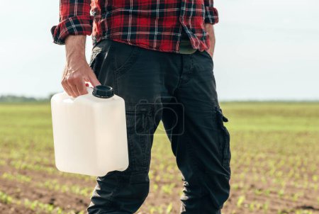 Photo for Corn crop protection concept, male farmer agronomist holding jerry can container canister with pesticide, selective focus - Royalty Free Image