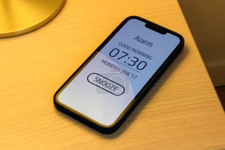 Téléchargez les photos : Réveil Smartphone sur table de nuit de chambre avec bouton Snooze, mise au point sélective - en image libre de droit