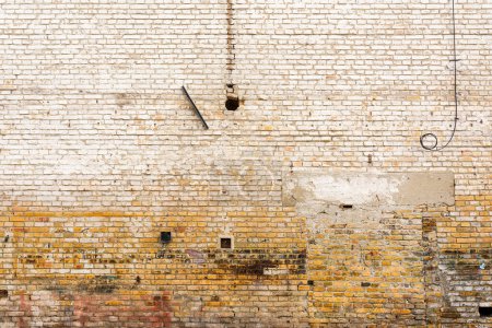 Foto de Textura de fachada de pared de ladrillo viejo con pintura blanca despegando de la superficie como fondo - Imagen libre de derechos