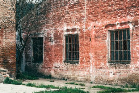 Foto de Vieja ventana de rejilla metálica industrial con mullion y muntin en el edificio de fábrica en ruinas, vidrio roto y pared de ladrillo desgastado - Imagen libre de derechos