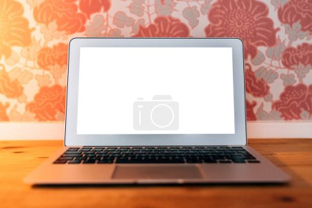 Foto de Ordenador portátil con pantalla de maqueta blanca en blanco en el escritorio de la sala de estar, enfoque selectivo - Imagen libre de derechos