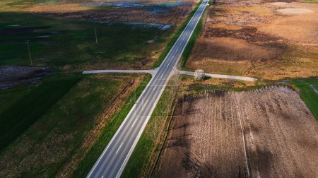 Téléchargez les photos : Vue aérienne de la route vide à travers le paysage de la plaine au printemps, vue en angle élevé du drone pov - en image libre de droit