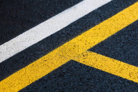 Téléchargez les photos : Marquage routier sur toute nouvelle surface asphaltée d'un parking, lignes jaunes et blanches comme fond abstrait en perspective - en image libre de droit