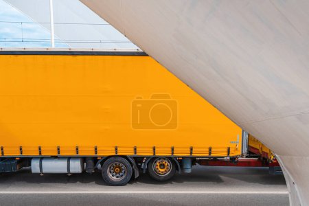 Téléchargez les photos : Camion jaune remorque sur la route, semi-camion dix-huit roues traversant le pont, mise au point sélective - en image libre de droit