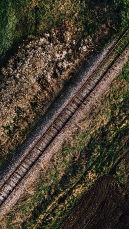 Photo for Aerial shot of railroad track running through cultivated countryside landscape in spring, high angle view, drone pov - Royalty Free Image