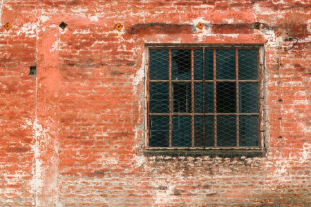 Foto de Vieja ventana de rejilla metálica industrial con mullion y muntin en el edificio de fábrica en ruinas, vidrio roto y pared de ladrillo desgastado - Imagen libre de derechos