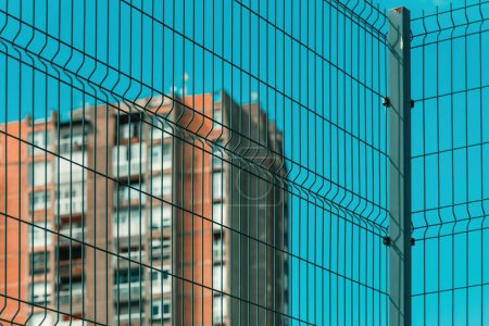 Photo for High rise architectural brutalism style apartment building behind metal fence, selective focus - Royalty Free Image