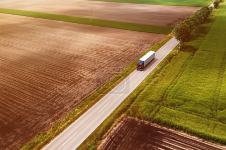 Téléchargez les photos : Grand semi-camion sur route de campagne vu du point de vue du drone, prise de vue aérienne du concept de camionnage et de logistique, vue grand angle - en image libre de droit